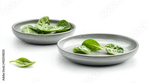 Two ceramic plates with fresh green spinach leaves isolated on a white background for food-related designs or healthy eating concepts.. Generative AI
