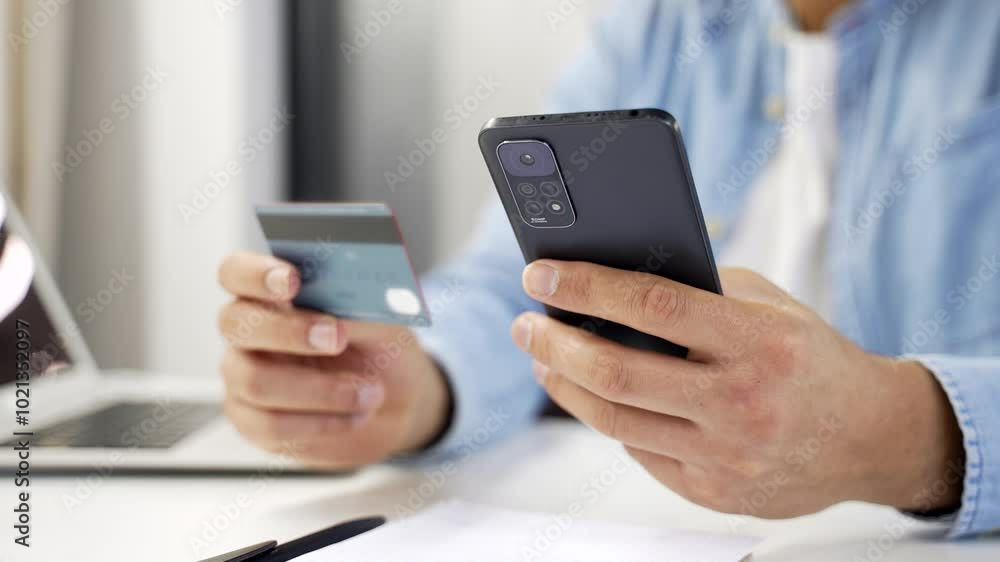 Close up of african american male hands using phone to make online transaction with credit card in business office. Shopper makes payment, pays bills, spends money on internet, Digital payment Close up of african american male hands using phone to make online transaction with credit card in business office. Shopper makes payment, pays bills, spends money on internet, Digital payment