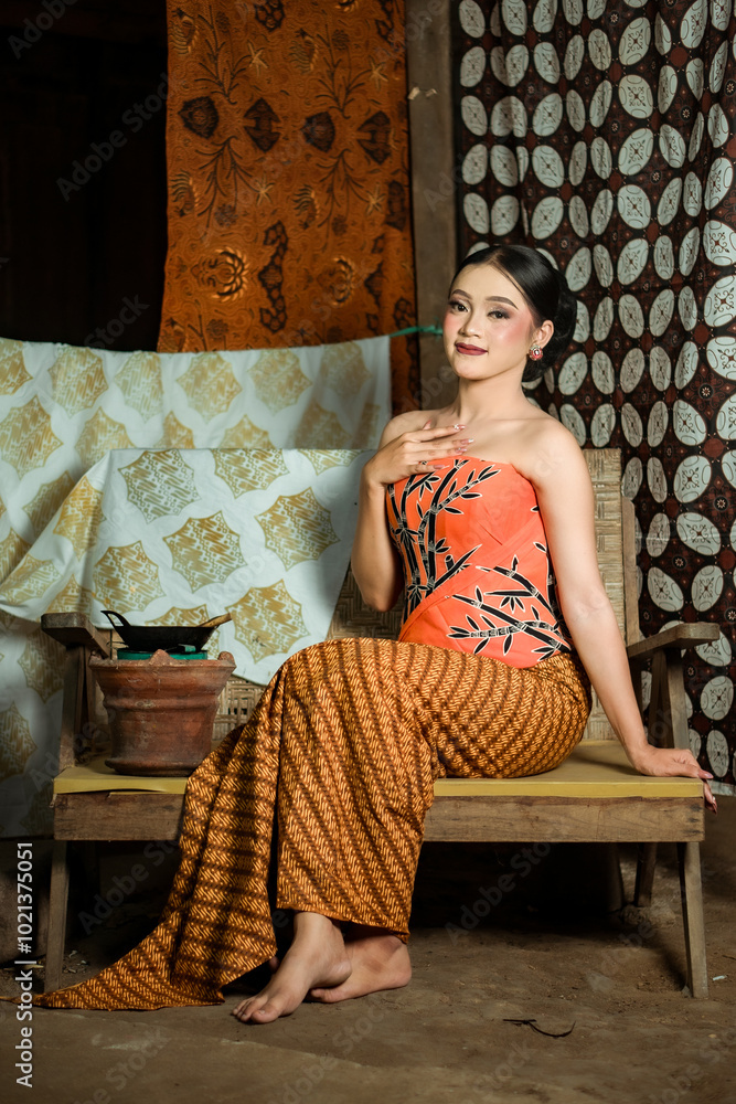 Fototapeta premium Young Indonesian women or fashion models wearing traditional Indonesian clothing or attire with batik motifs from Indonesian culture. Making or painting batik cloth. Making batik cloth.