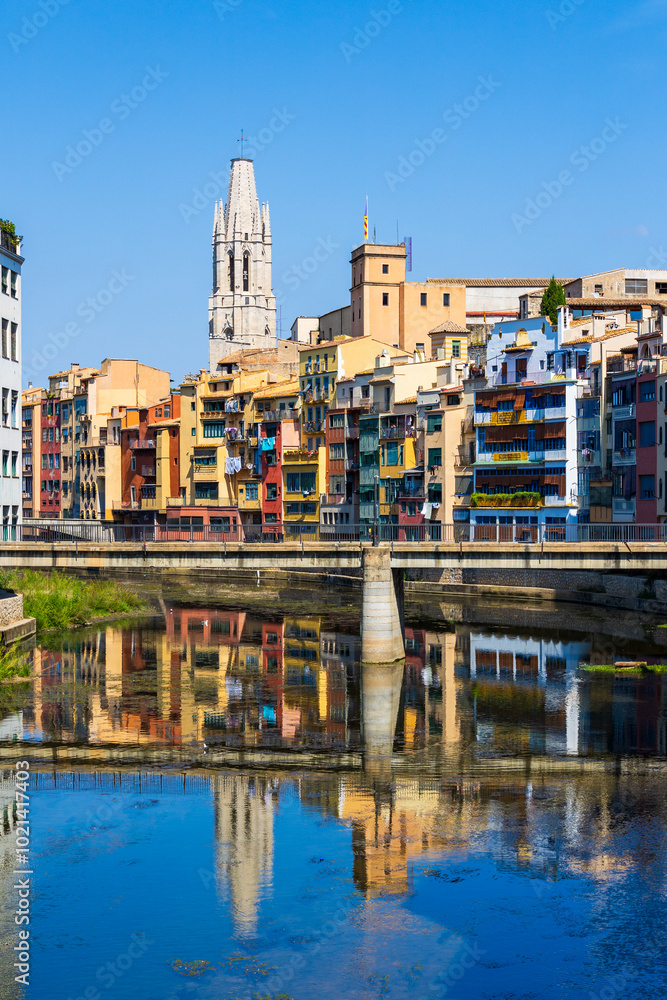 Fototapeta premium Clocher de style gothique de la Basílica Sant Feliu de Gérone dominant le Riu Onyar et ses immeubles colorés