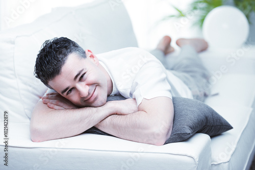 Handsome man relaxing on sofa at home smiling