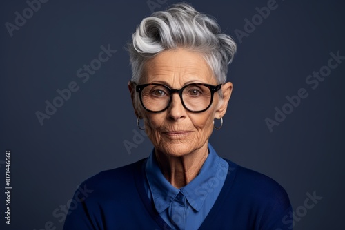 Portrait of a happy senior woman wearing eyeglasses against blue background