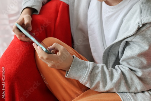 Close up of a boy's hands holding a smartphone and playing a game on the smartphone
