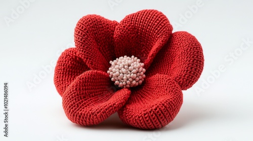 A charming, red knitted flower stands out against a plain white backdrop.