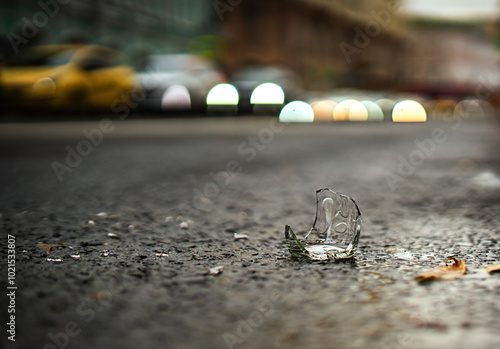 Wallpaper Mural broken glass bottle with sharp edges rests on a paved road, a stark reminder of negligence. Its transparent shards glimmer dangerously, posing risks to passing vehicles and pedestrians alike Torontodigital.ca