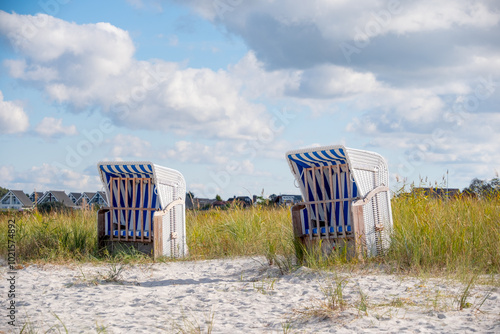 Fototapeta Naklejka Na Ścianę i Meble -  weiß blauer Strandkorb vor Ferienhäusern am Strand