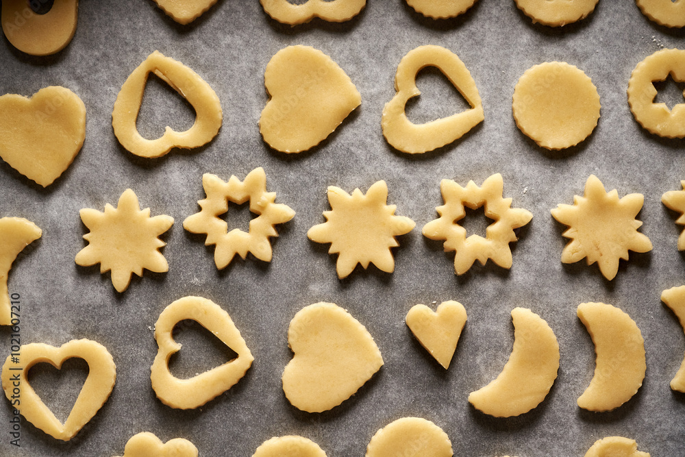 Shapes made of raw pastry dough on a sheet of baking paper - preparation of Linzer Christmas cookies Shapes made of raw pastry dough on a sheet of baking paper - preparation of Linzer Christmas cookies