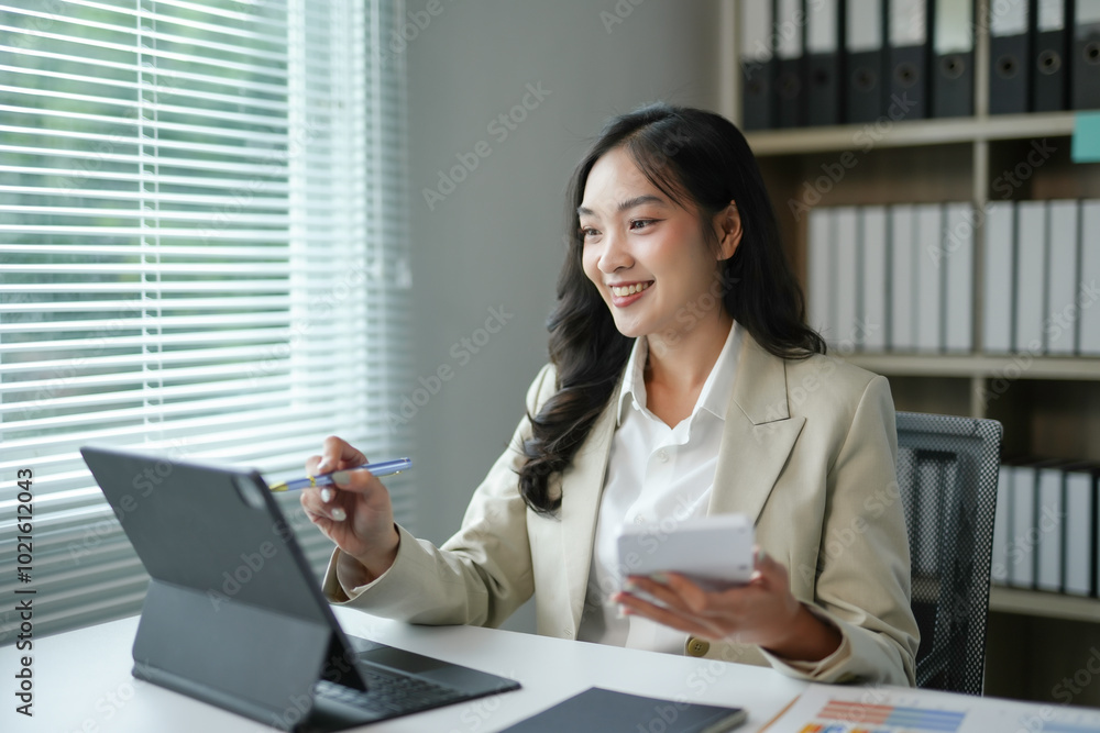 Smiling businesswoman using digital tablet and calculator, working on business project in modern office Smiling businesswoman using digital tablet and calculator, working on business project in modern office