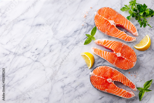 Salmon steaks, fillet with herbs and spices. White marble background. Copy space. Top view. photo