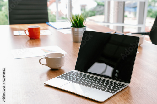 Laptop computer with opened lid on table in meeting room of office workspace. uds