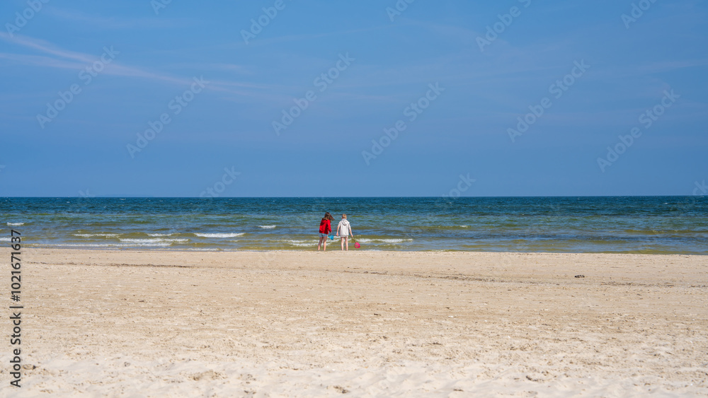 Obraz premium Cute children standing on beach and looking at sea. Boy and girl are enjoying vacation at sea. Family vacation. Vacation with children on the Baltic Sea. Germany