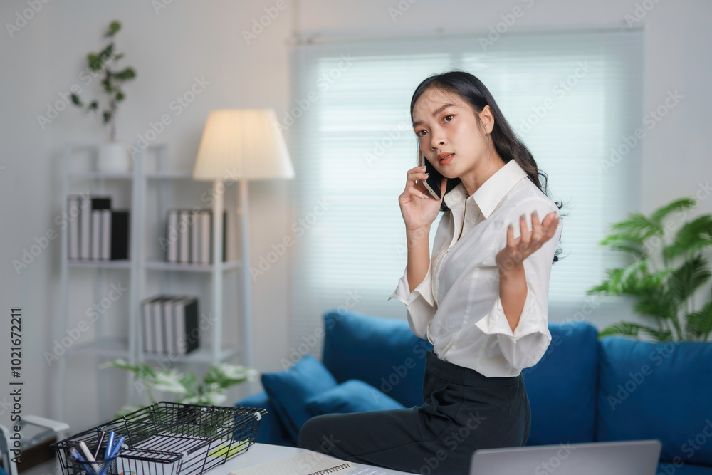 Businesswoman is sitting on her desk talking on her phone and gesturing with her other hand, having a difficult conversation Businesswoman is sitting on her desk talking on her phone and gesturing with her other hand, having a difficult conversation