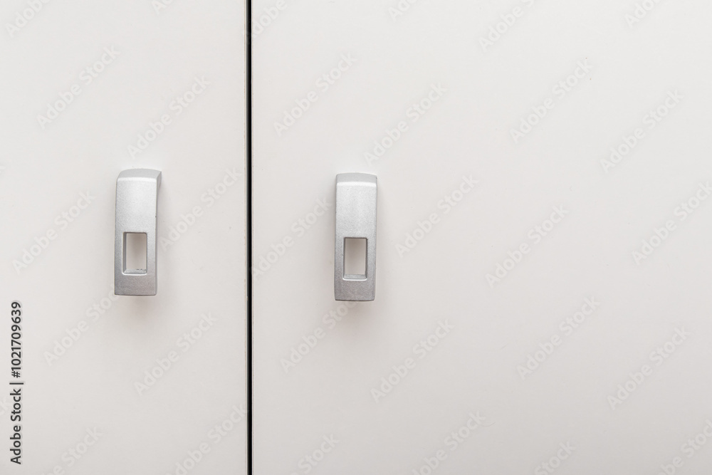 Handles on white wooden swing cabinet. Furniture fittings. Small silver furniture handles Handles on white wooden swing cabinet. Furniture fittings. Small silver furniture handles