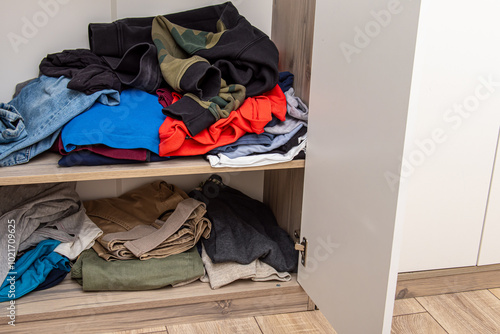 Messy closet. Chaos in the wardrobe. Sloppily folded clothes photo