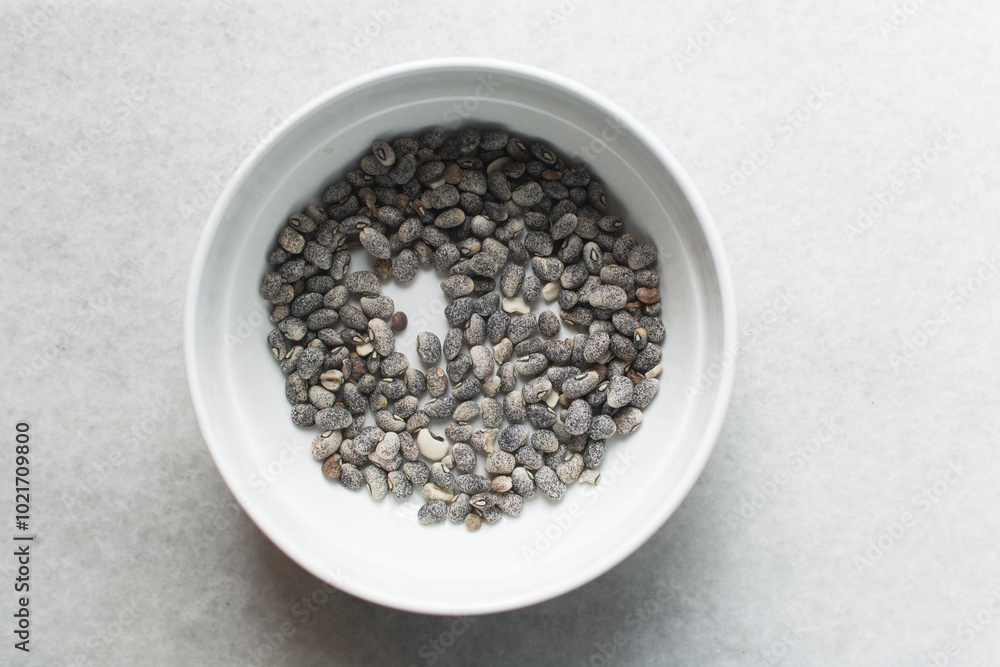 overhead view of blue speckled beans in a white bowl, top view of nigerian army beans, speckled heirloom beans in a ceramic bowl overhead view of blue speckled beans in a white bowl, top view of nigerian army beans, speckled heirloom beans in a ceramic bowl