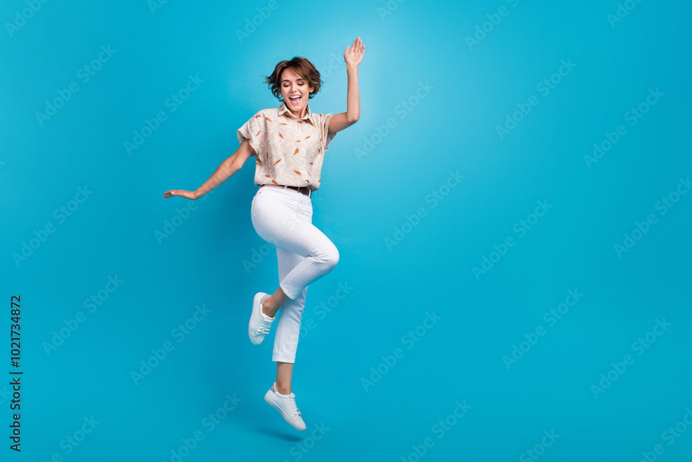 Full length photo of cheerful optimistic girl dressed stylish clothes jump up empty space isolated on blue color background Full length photo of cheerful optimistic girl dressed stylish clothes jump up empty space isolated on blue color background