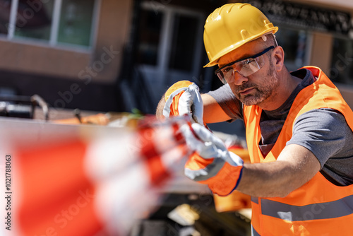 A construction worker secures a safety barrier tape on a sunny day