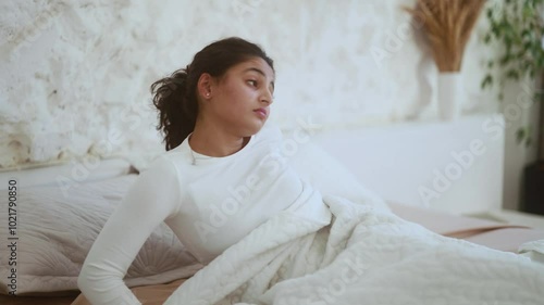 Sad sleepy young indian woman waking up in bad mood lying in bed at light room Unhappy female feeling annoying about early morning before study or work in bedroom Bad morning day