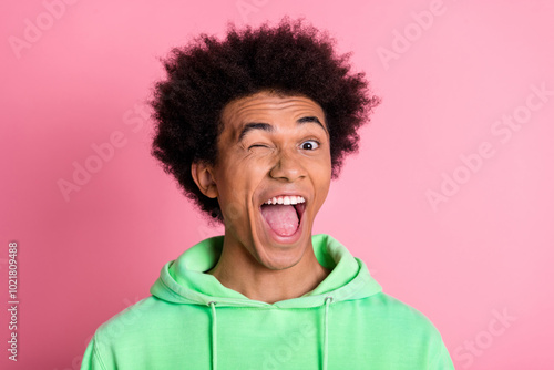 Photo of nice young man eye wink blink wear green hoodie isolared on pink color background