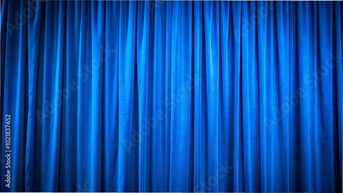 Close-up of a blue curtain with vertical folds, spotlighted in a theater setting, showcasing rich blackout fabric texture. photo