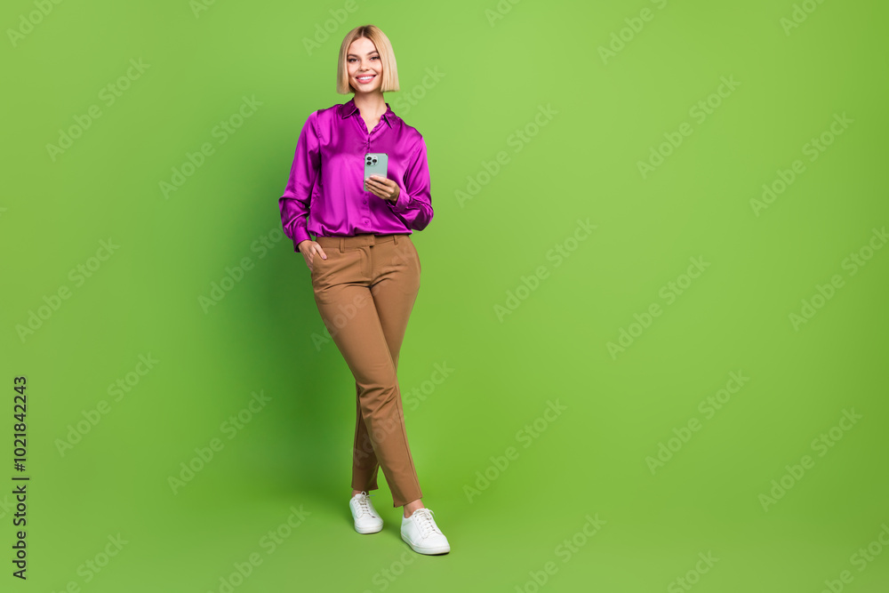 Full size photo of pretty young woman hold smart phone empty space wear shirt isolated on green color background Full size photo of pretty young woman hold smart phone empty space wear shirt isolated on green color background