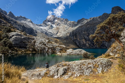 Obraz na płótnie Woman Sits by Churup Lagoon with Turquoise Waters Beneath the Snow-Capped Peak of the Cordillera Blanca in the Huascaran National Park, in Ancash, Peru w salonie