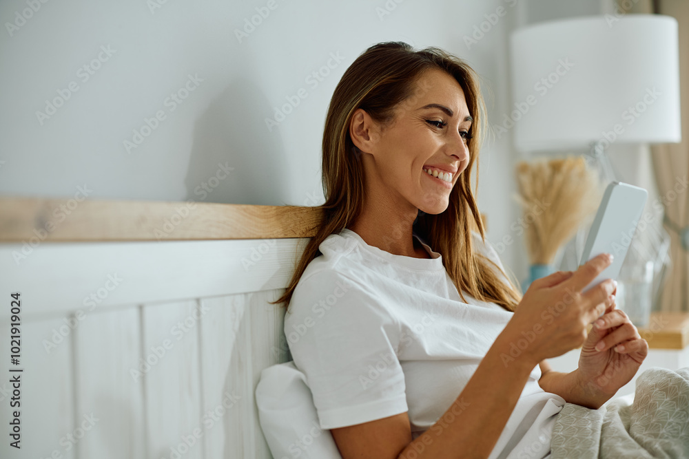 Young happy woman using mobile phone in bedroom. Young happy woman using mobile phone in bedroom.