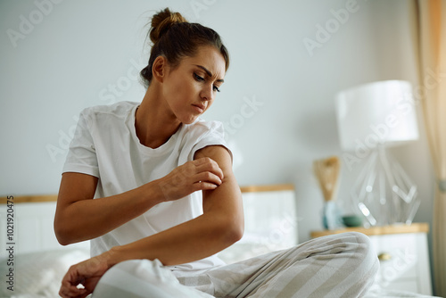 Young woman scratching itchy skin on her arm.
