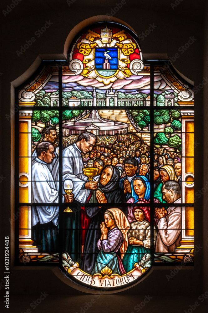 Obraz premium A priest distributing Communion to the faithful. A stained-glass window in the Basilica of Our Lady of the Rosary in Fatima, Portugal.