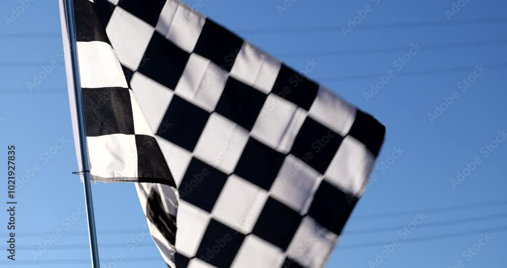 Checkered racing flag blows in the wind at a race car track finish line ...