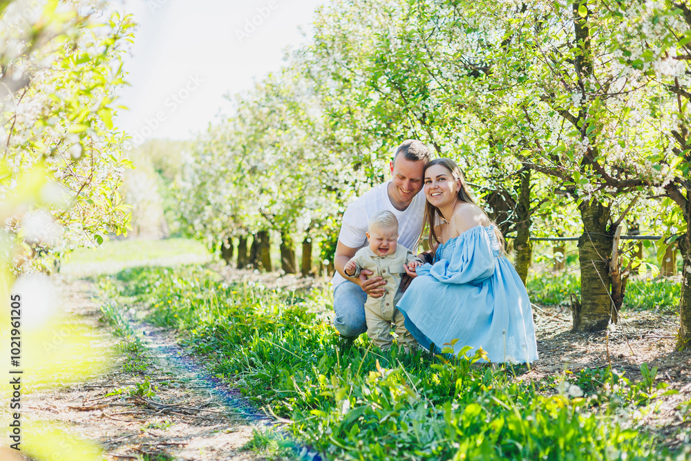 Fototapeta premium A young married couple, a man, a woman and a little son, are walking in the park. Time for a walk, mom, dad and small child.