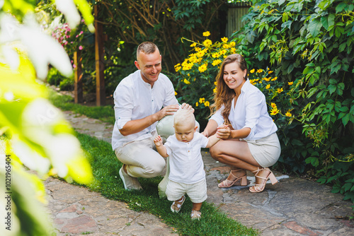 Two parents are playing on a walk with their toddler son. A young married couple, a man, a woman and a little son, are walking in the park. Time for a walk, mom, dad and small child. photo