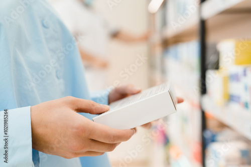 Cropped closeup image of female young customer buyer client hands holding drug medicine container, reading ingredients, side effects of pills, painkillers, antibiotics in pharmacy drugstore