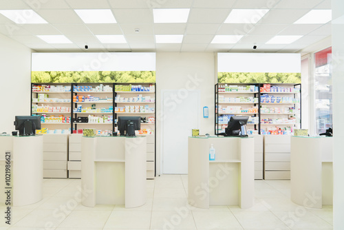 Four empty without visitors clients staff cash point desks at pharmacy drugstore chemist`s store with white shelves full of medicines, jars with pills, remedy photo