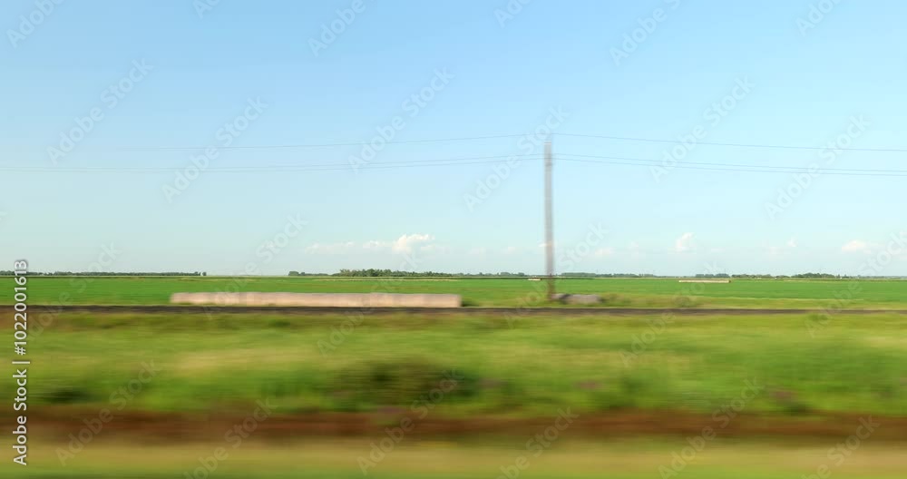 Driving plate side view on a highway through open plains and farmland in Midwestern United States agricultural fields under a wide sky rural travel and American heartland concept Driving plate side view on a highway through open plains and farmland in Midwestern United States agricultural fields under a wide sky rural travel and American heartland concept