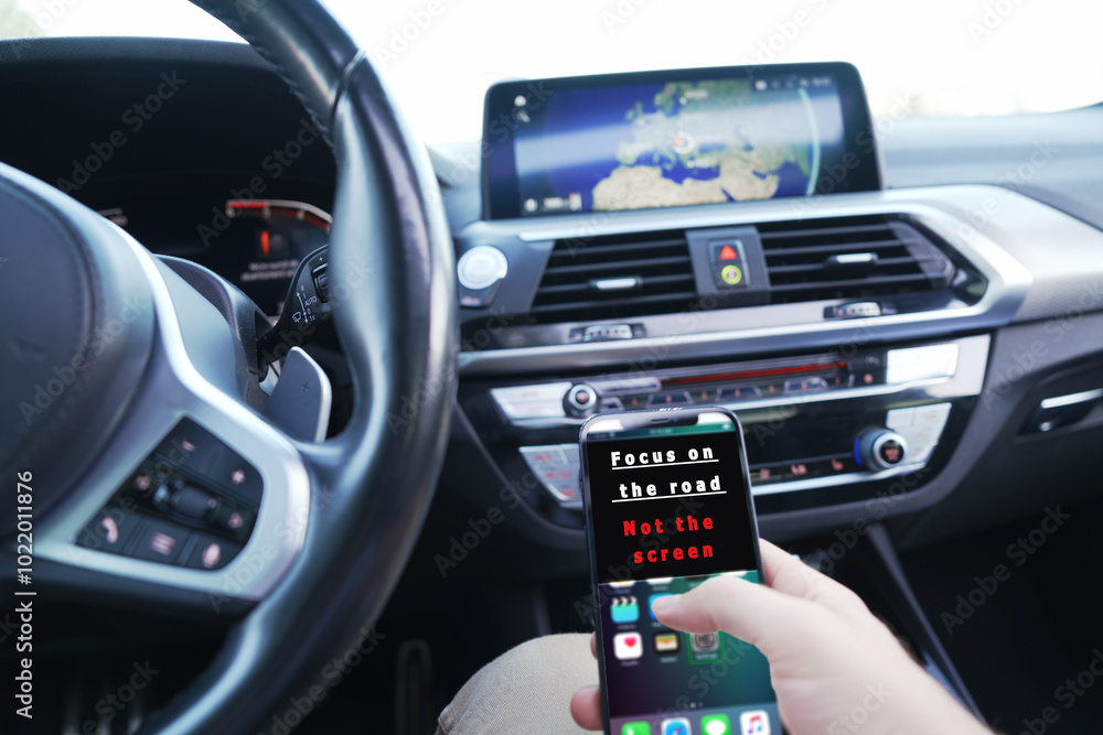 focus on the road not the screen. someone with the phone in his hand, driving focus on the road not the screen. someone with the phone in his hand, driving