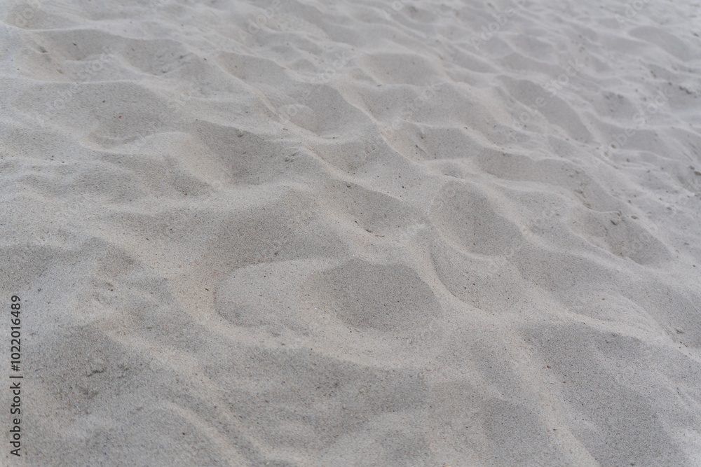 Background with beach sea sand texture. An image of the sandy surface with natural patterns and lines created by the wind and footsteps of tourists. Background with beach sea sand texture. An image of the sandy surface with natural patterns and lines created by the wind and footsteps of tourists.
