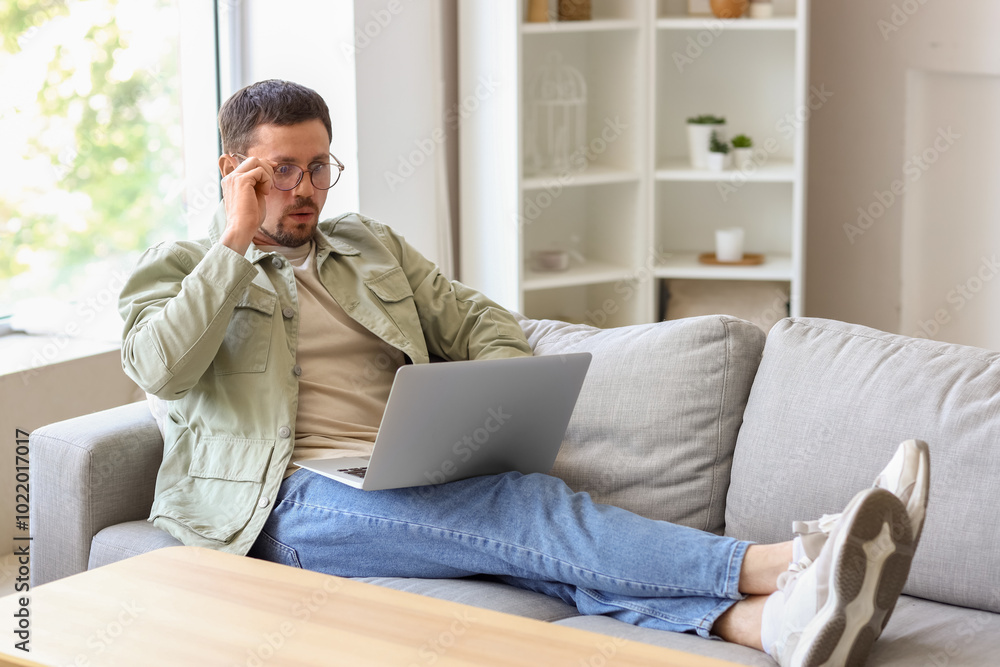 Handsome man in stylish eyeglasses using laptop at home Handsome man in stylish eyeglasses using laptop at home