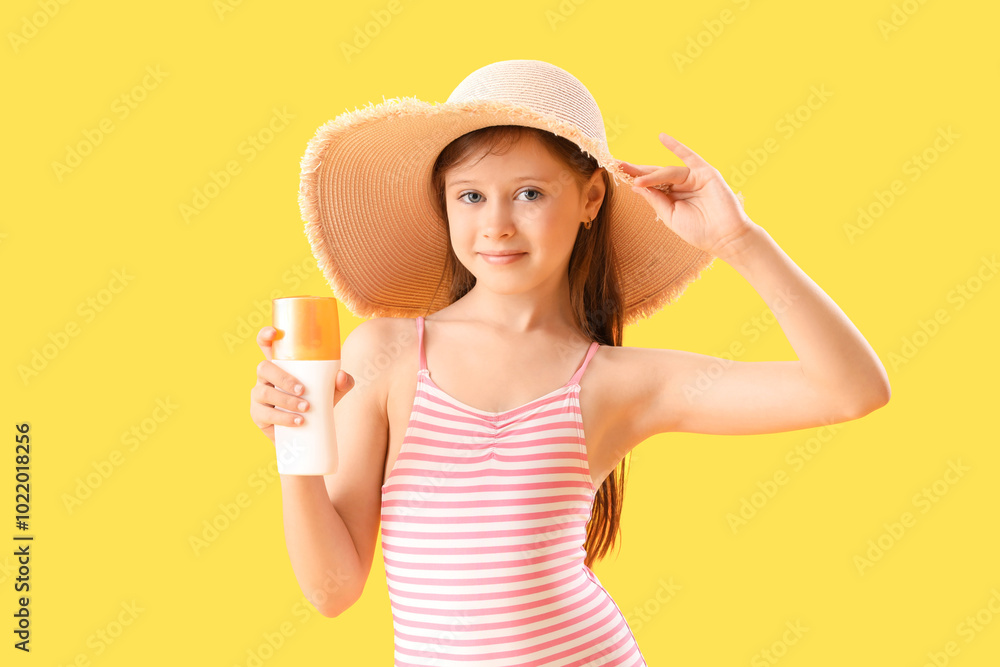 Little girl with bottle of sunscreen cream on yellow background Little girl with bottle of sunscreen cream on yellow background