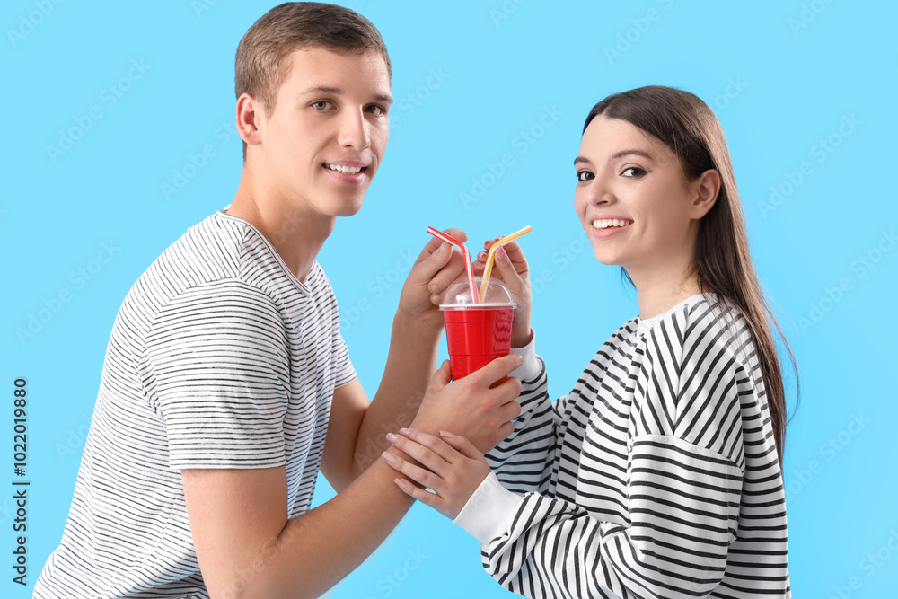 Happy young couple drinking soda on blue background Happy young couple drinking soda on blue background