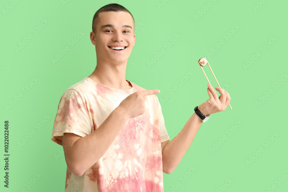 Young man with tasty sushi roll on green background Young man with tasty sushi roll on green background