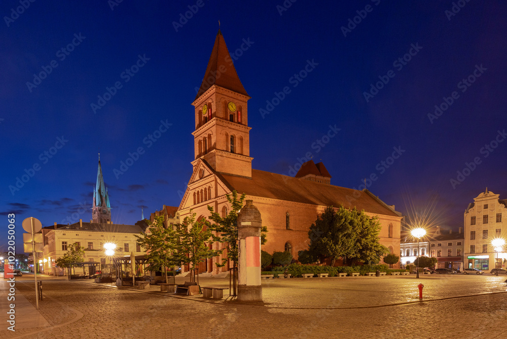 Obraz premium Early morning view of St. Catherine's Church on the market square illuminated by street lamps, Torun, Poland
