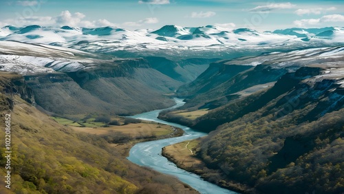 Landscape shot of a river flowing through valley with snow-capped mountains