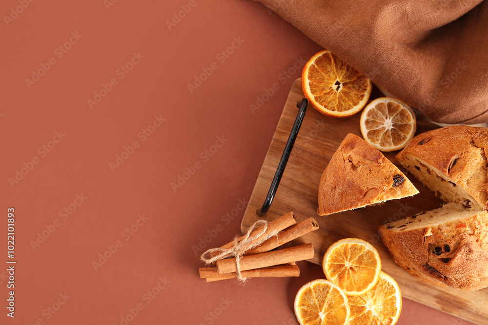 Wooden tray with tasty Panettone, slices of dried orange and cinnamon sticks on colorful background Wooden tray with tasty Panettone, slices of dried orange and cinnamon sticks on colorful background