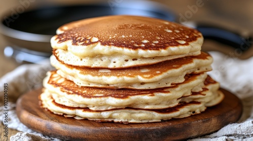 A stack of golden brown pancakes on a wooden board.