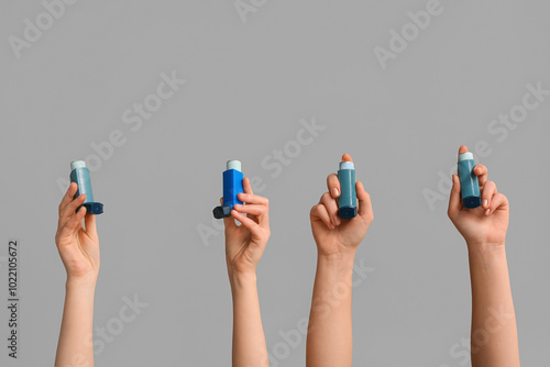 Female hands with modern asthma inhalers on grey background photo