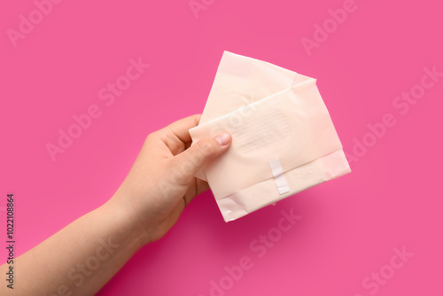 Female hand with menstrual pads on pink background photo