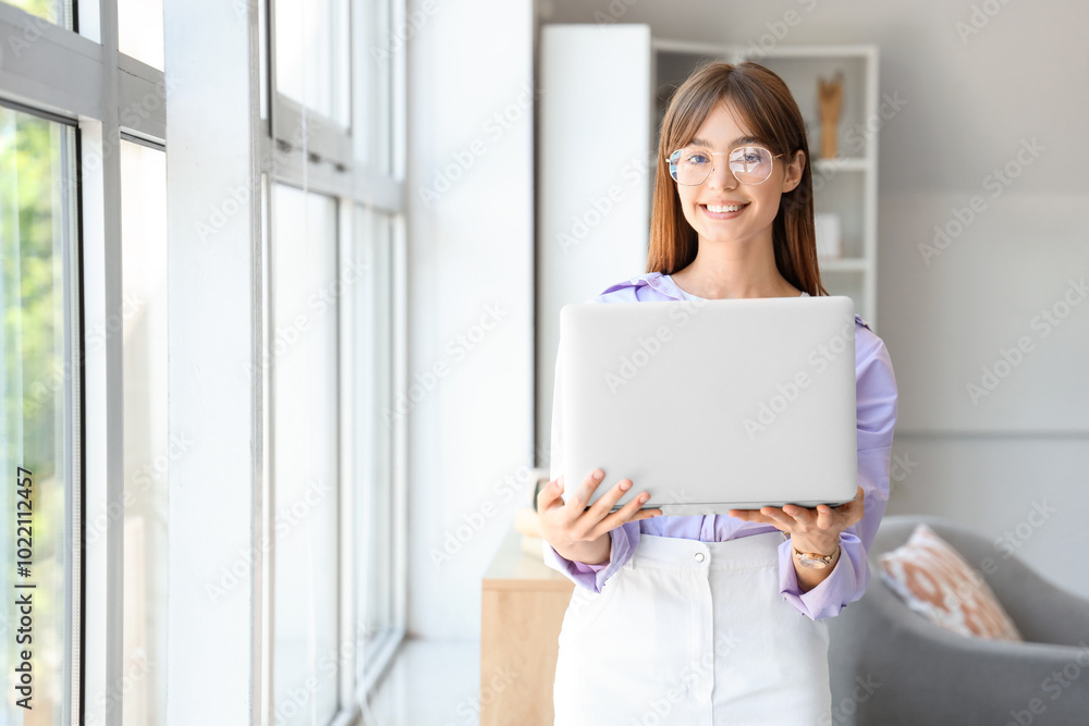 Young woman in eyeglasses with laptop near window at home Young woman in eyeglasses with laptop near window at home