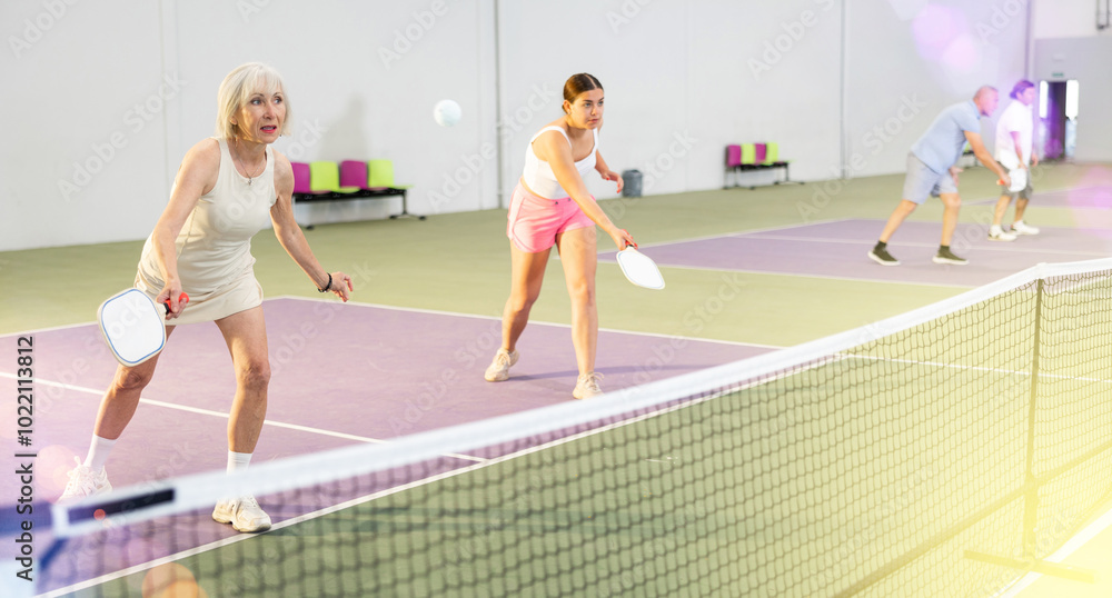 Obraz premium Athletic womens playing pickleball tennis on the pickleball court indoors