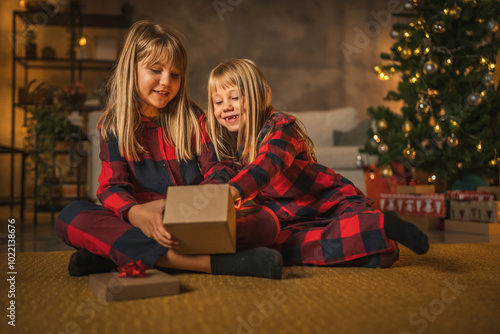 фотографія Sisters enjoy christmas gift in cozy living room setting